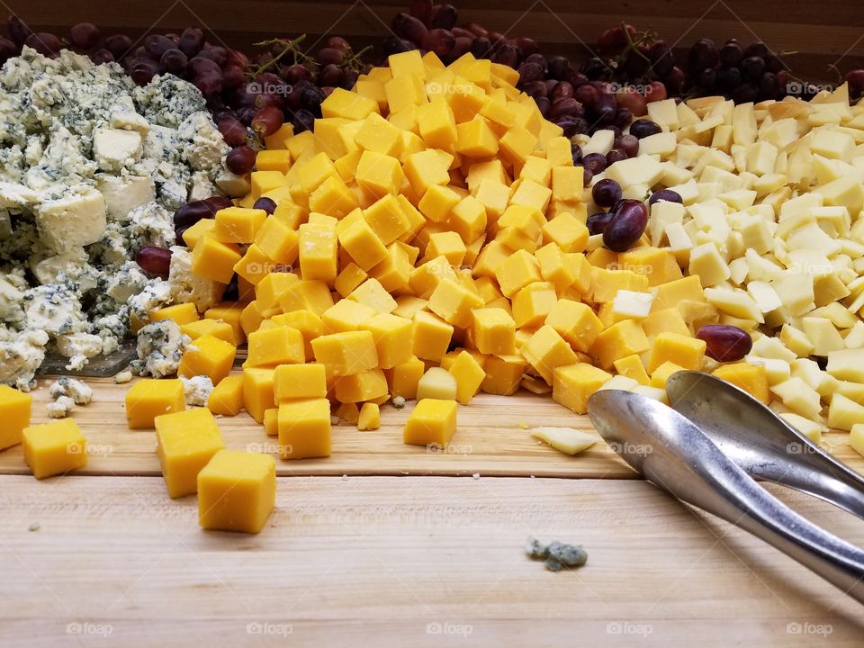 Various types of cheese with fruit on wooden table