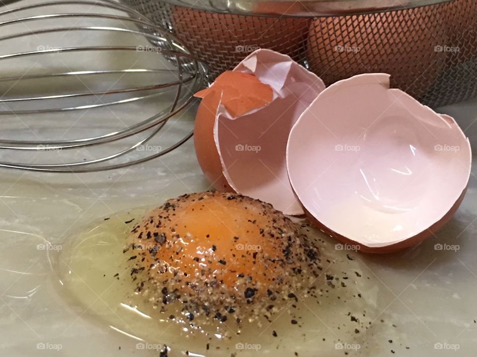 Raw seasoned brown egg on marble countertop closeup, food prep