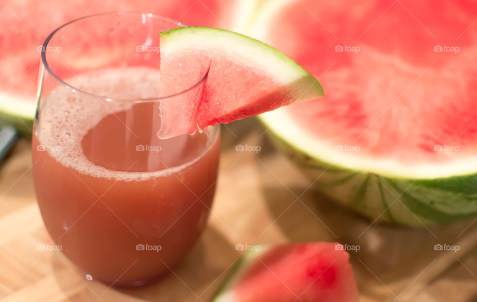 Freshly sliced pink seedless watermelon with home made juice freshly poured in glass on wood table background healthy summer cocktail and drink photography