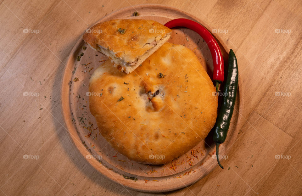 Fresh kubdari with peppers on the round wooden desk