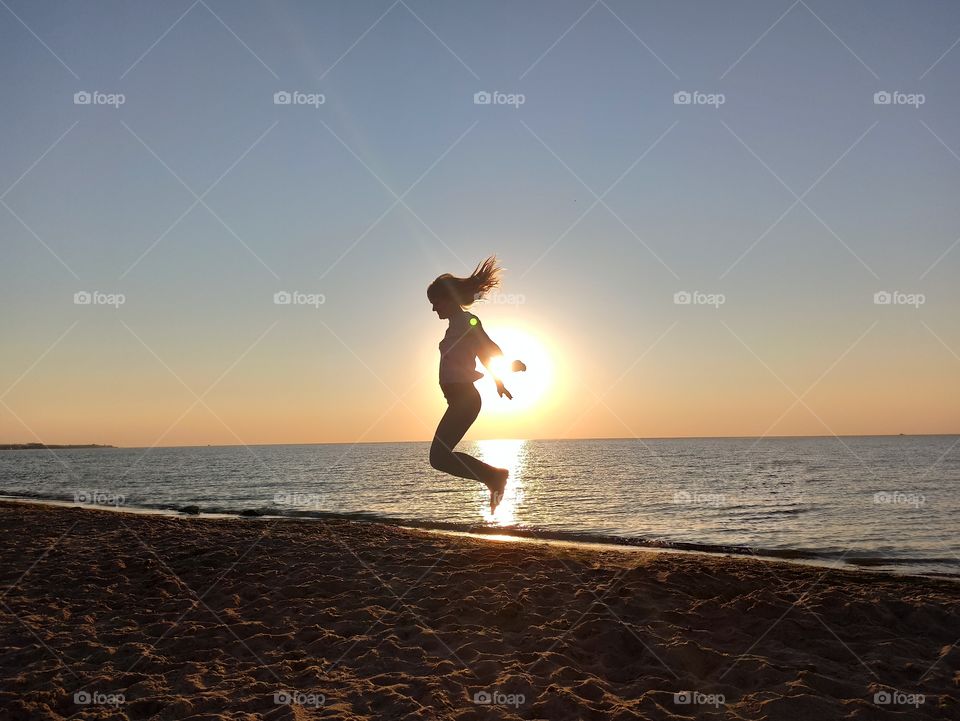 Bounce. Jumping girl at dawn on the seashore.