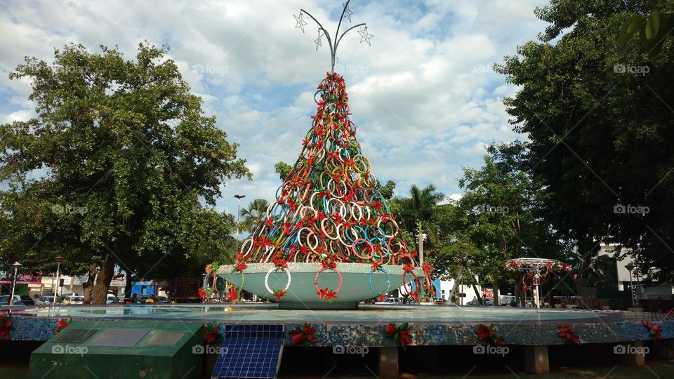 Reciclagem. Escultura de arvore de natal, sobre fonte de praça. Com muitos pneus velhos de bicicletas, pintados com varias cores.