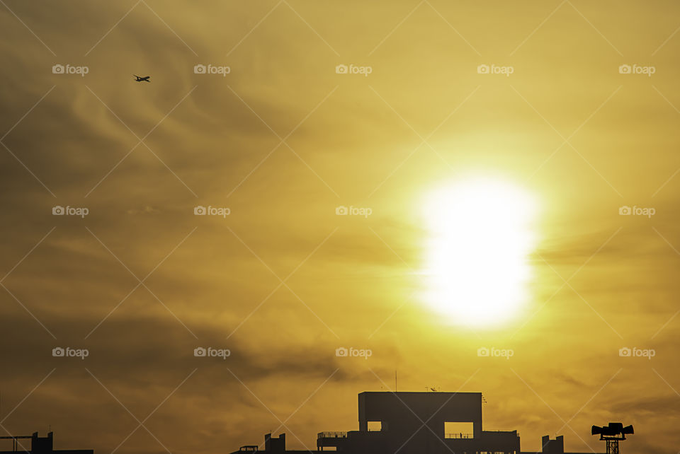 The early morning sunlight shining on buildings and the plane in the sky.