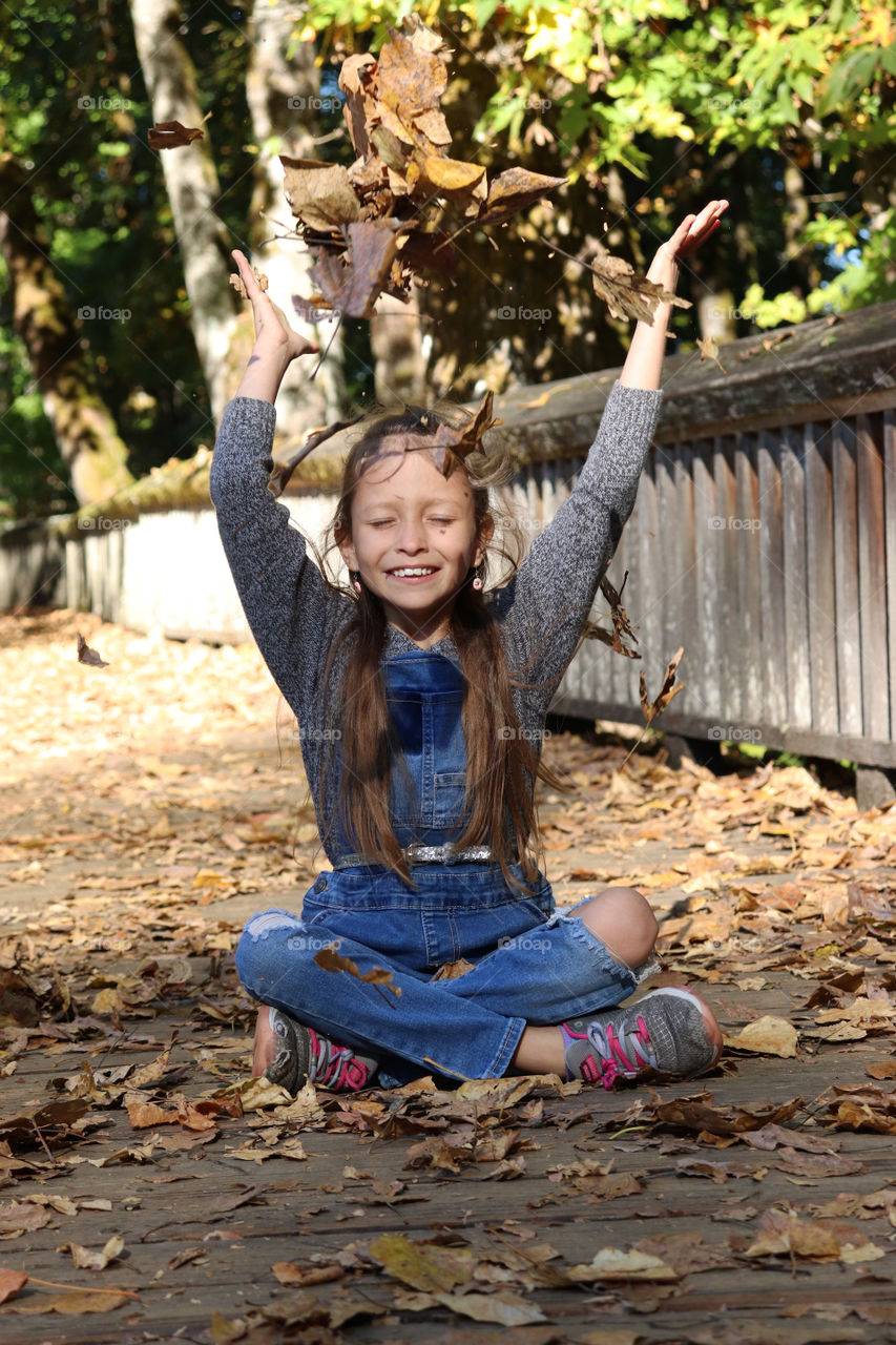 Girl playing in colorful fall leaves