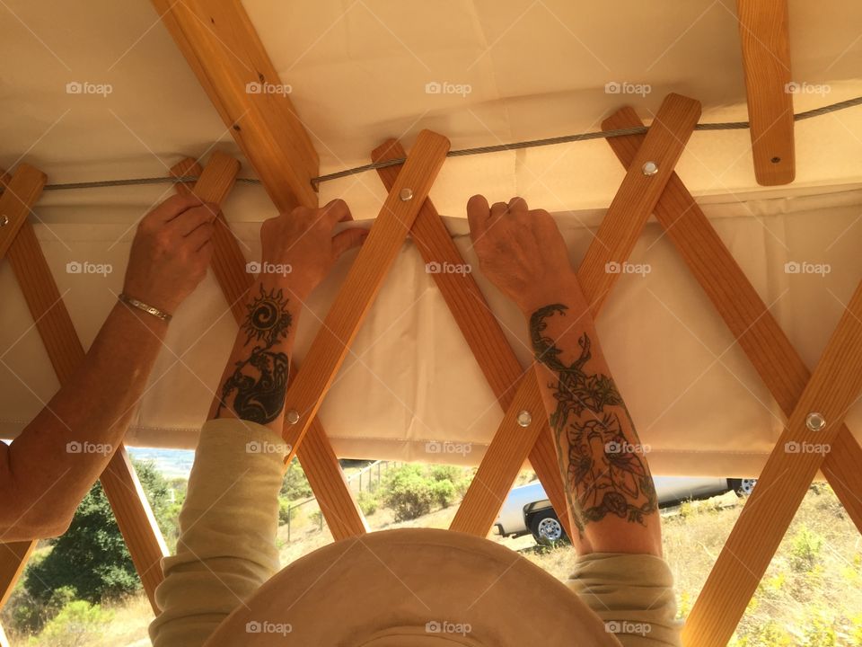 Building together . Woman's tattooed hands interior of yurt