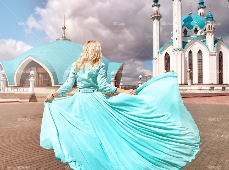 The girl in turquoise clothes on the background of a turquoise mosque