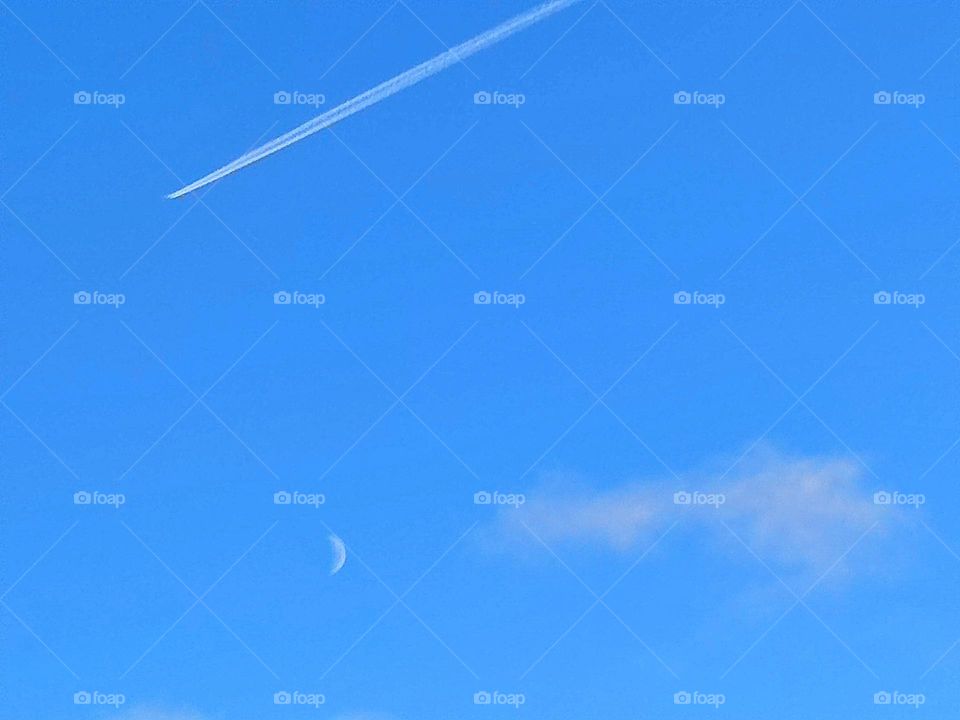 Minimalism.  Sunny day.  In the blue sky, a white stripe from a flying plane, a white crescent of the moon and a white cloud