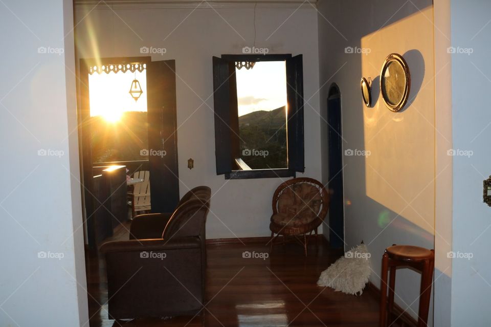 Sala com ar vintage e o por do sol invadindo pela porta trazendo luz e proporções 