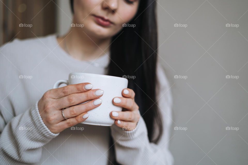 Crop photo of Beautiful smiling woman teenager girl with dark long hair in home clothes with the morning cup of coffee