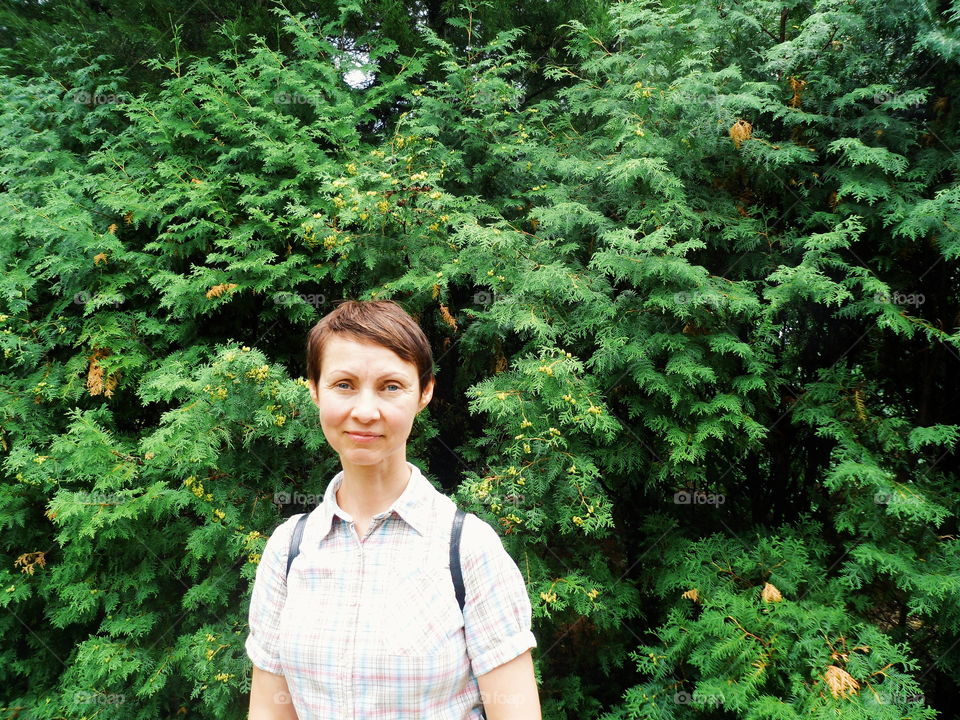 girl on the background of a bush with green leaves