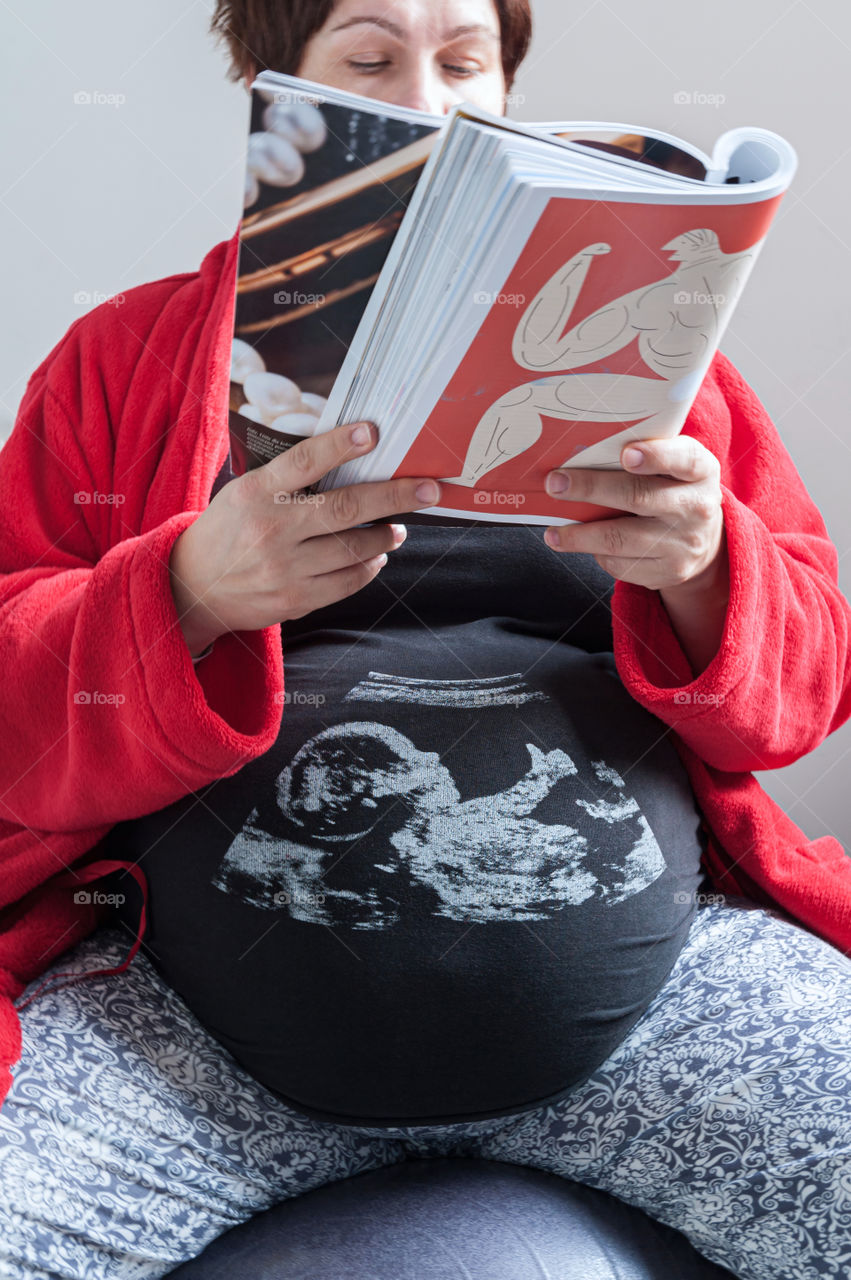 Pregnant woman reading magazine.