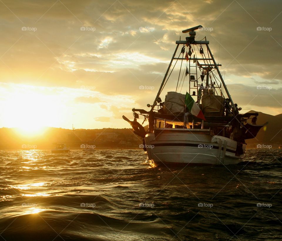 Fishing boat comes back home at sunset