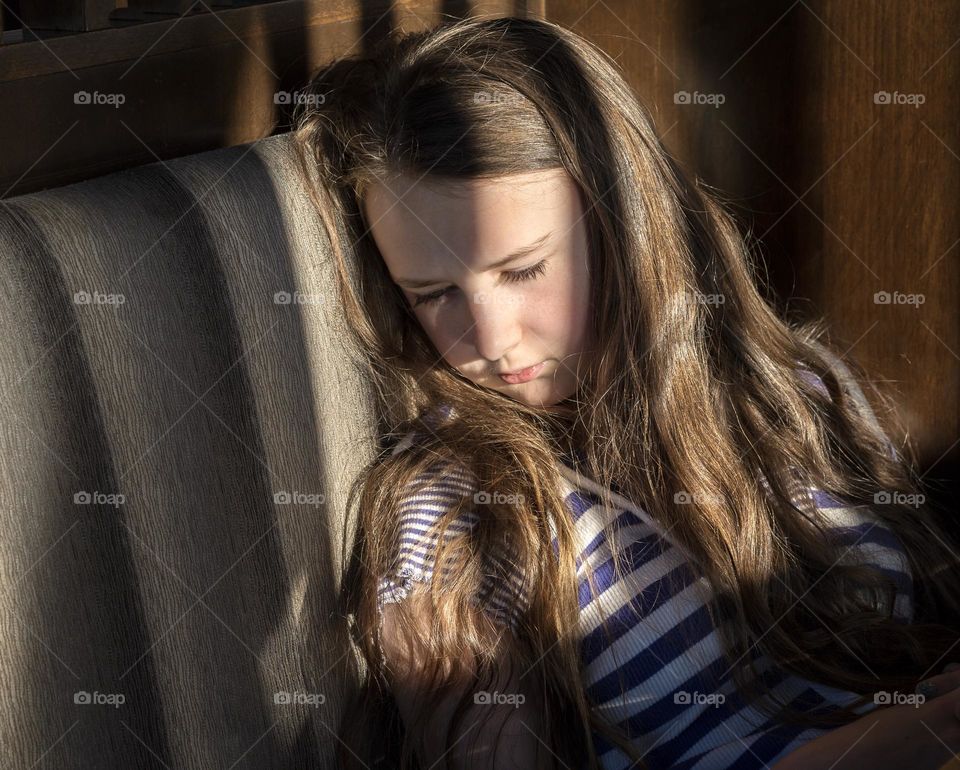 Girl in shadows looking down 