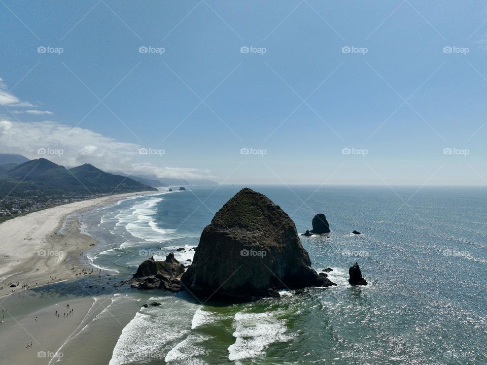 Haystack Rock standing tall amidst the serene beauty of Cannon Beach, where tide pools meet the endless horizon