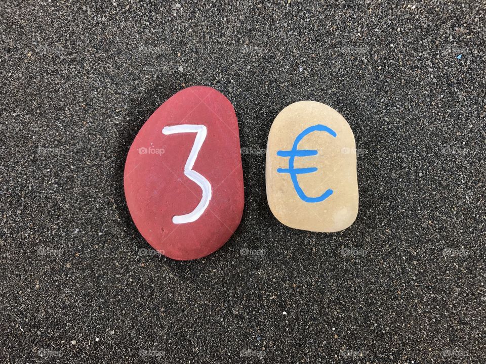 3 Euro with colored stones over black volcanic sand
