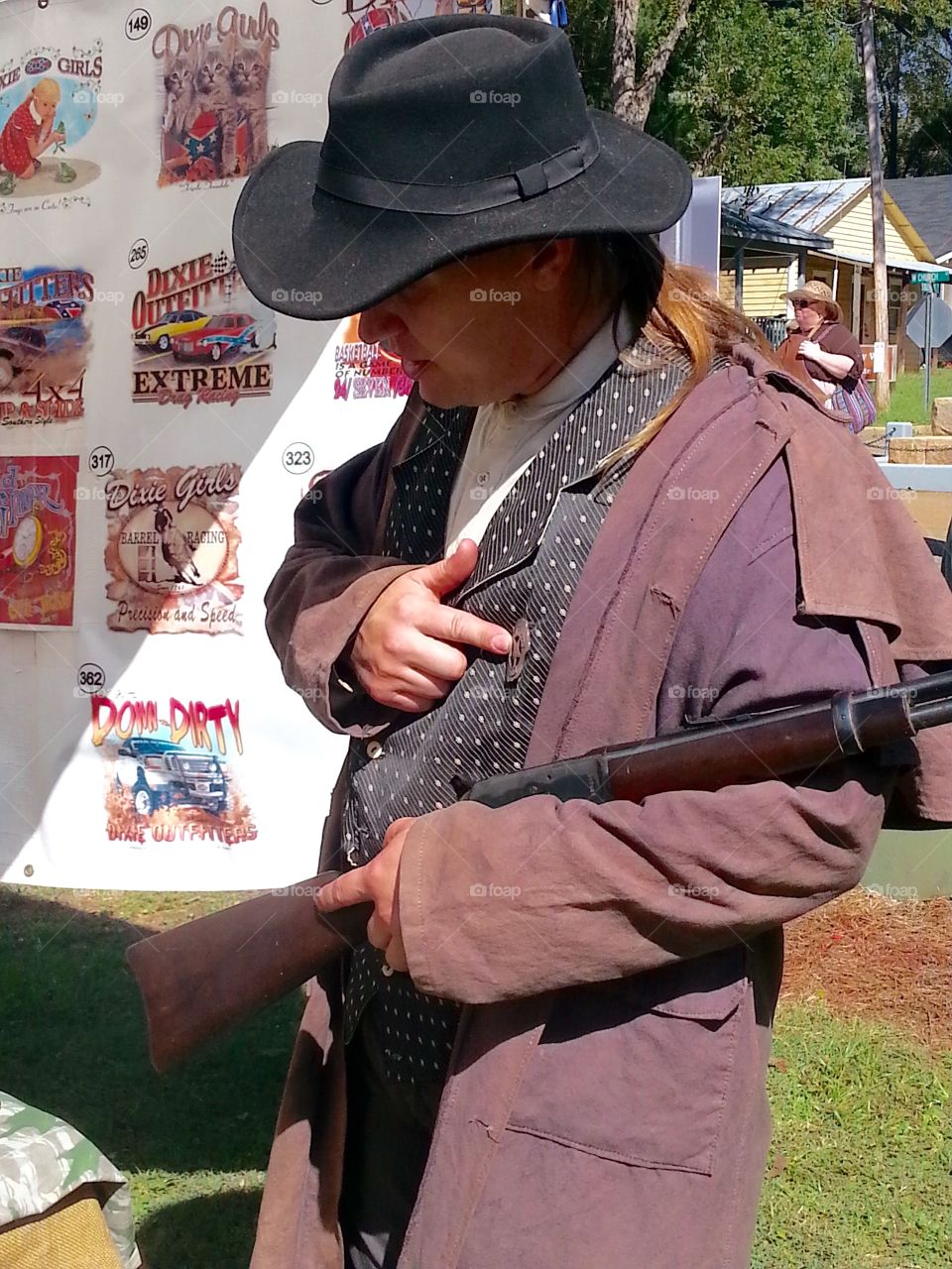 A man in full old time costume including hat and toting a gun in a reenactment from the civil war in 1800's. 
