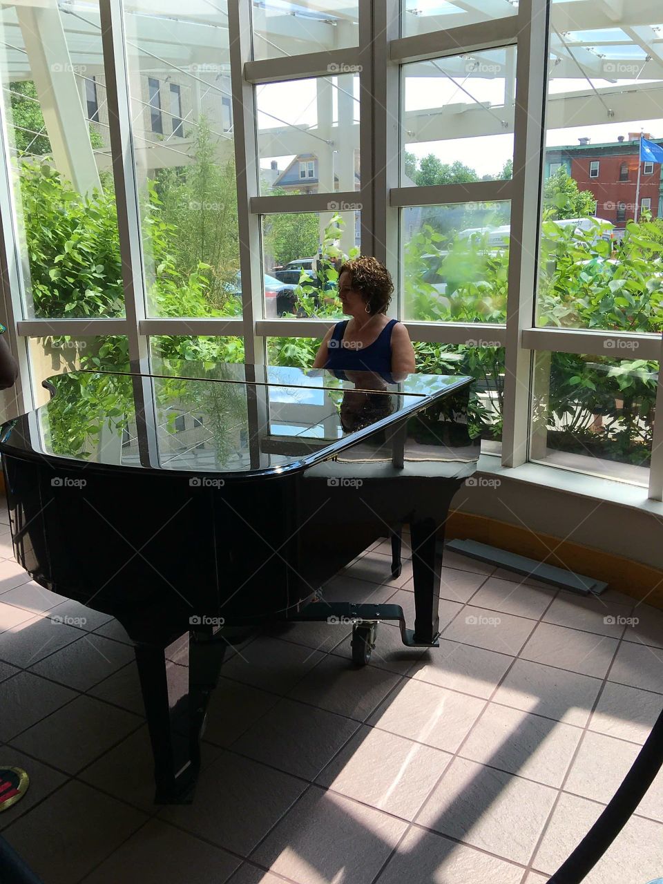 Piano player near large windows.