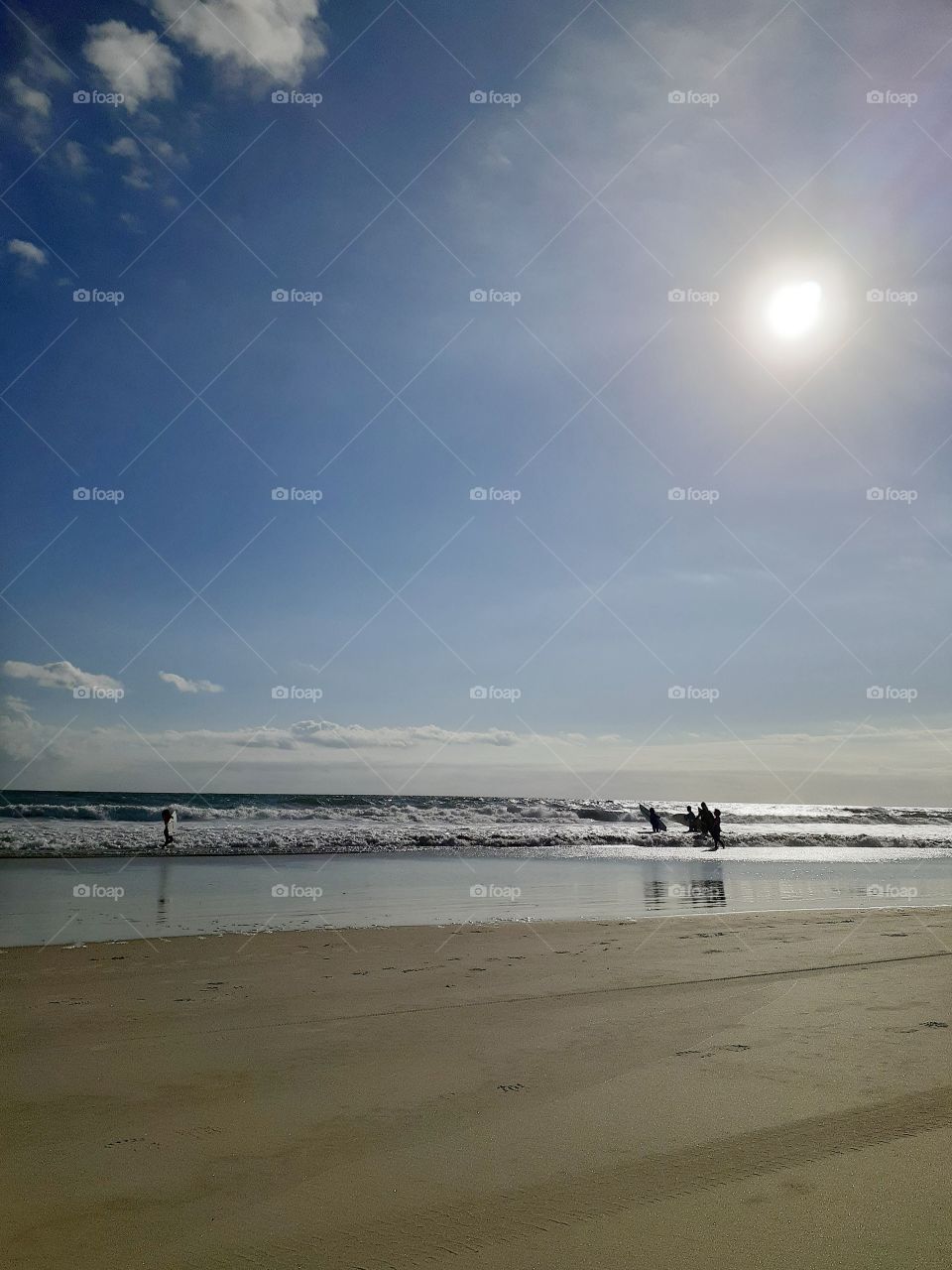 Three surfers carrying their surfboards head into the ocean at Indian Rocks Beach in Tampa, Florida.