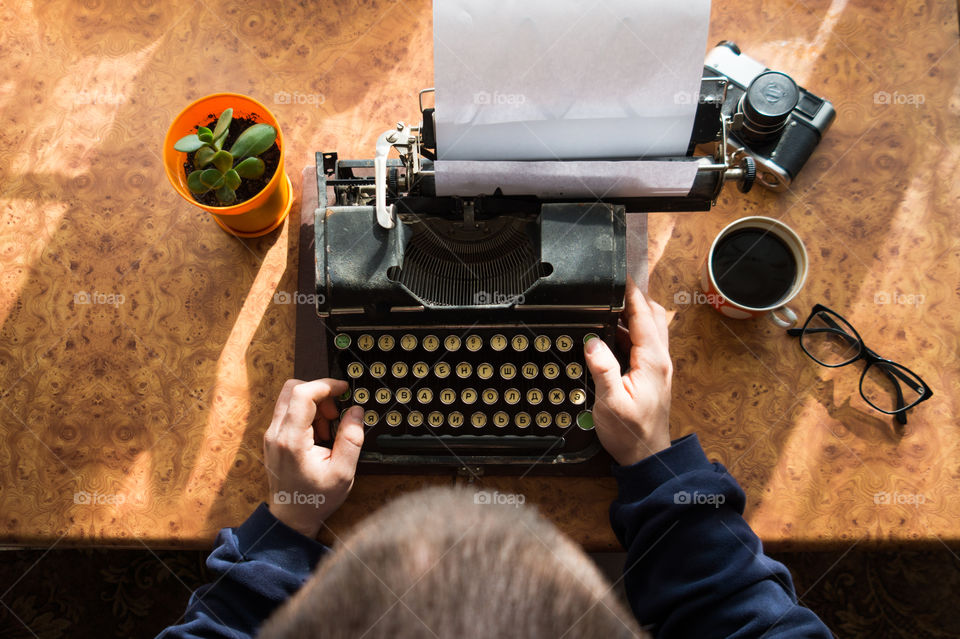A young writer is writing a new book on an old typewriter.