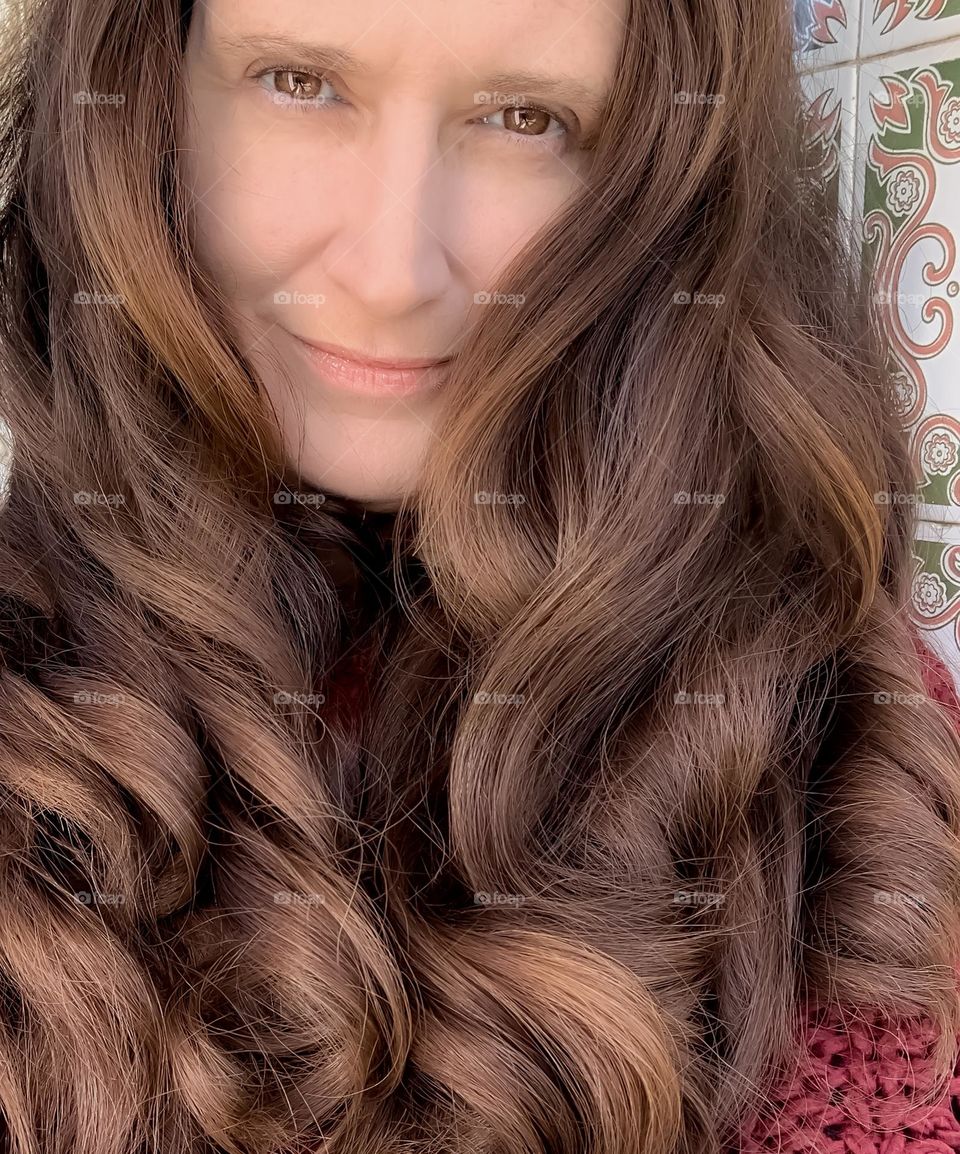 Middle-aged woman with long, curly hair in shades of brown