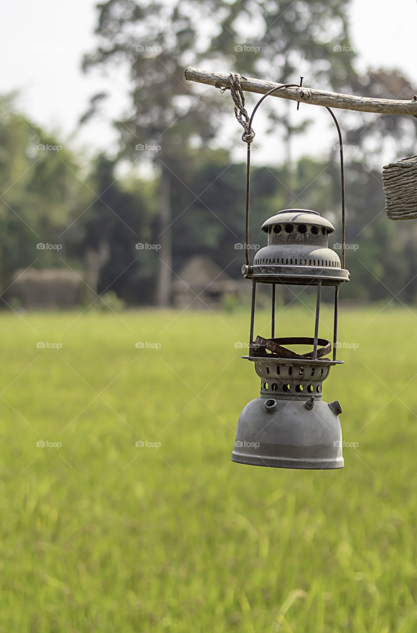 Old lantern hanging on wooden background fields.