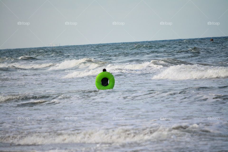 Lone Swimmer Braves the Ocean with a Green Float