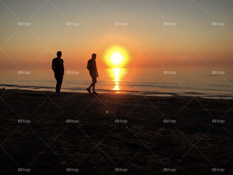 Two men walking on the beach in the sunshine