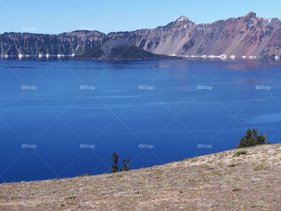 Wizard Island reflecting in the rich blue waters of Crater Lake in the forests of Southern Oregon on a sunny summer morning. 