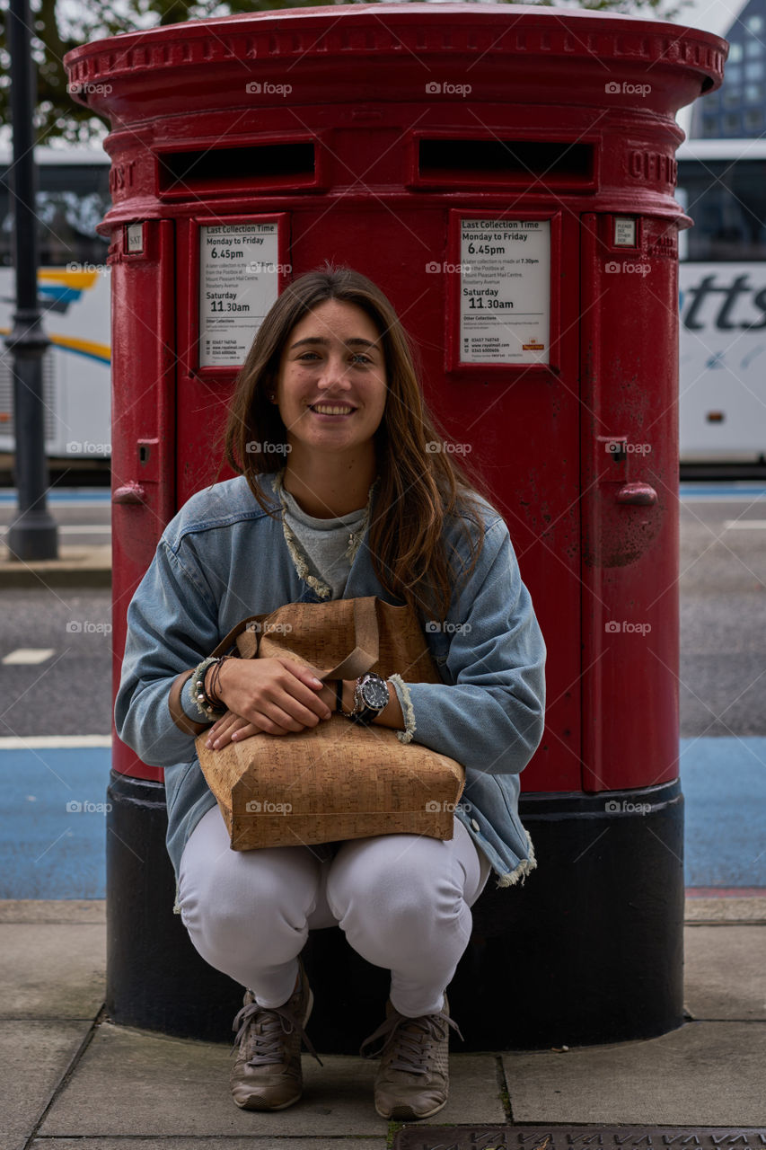 Young woman sitting near the postbox