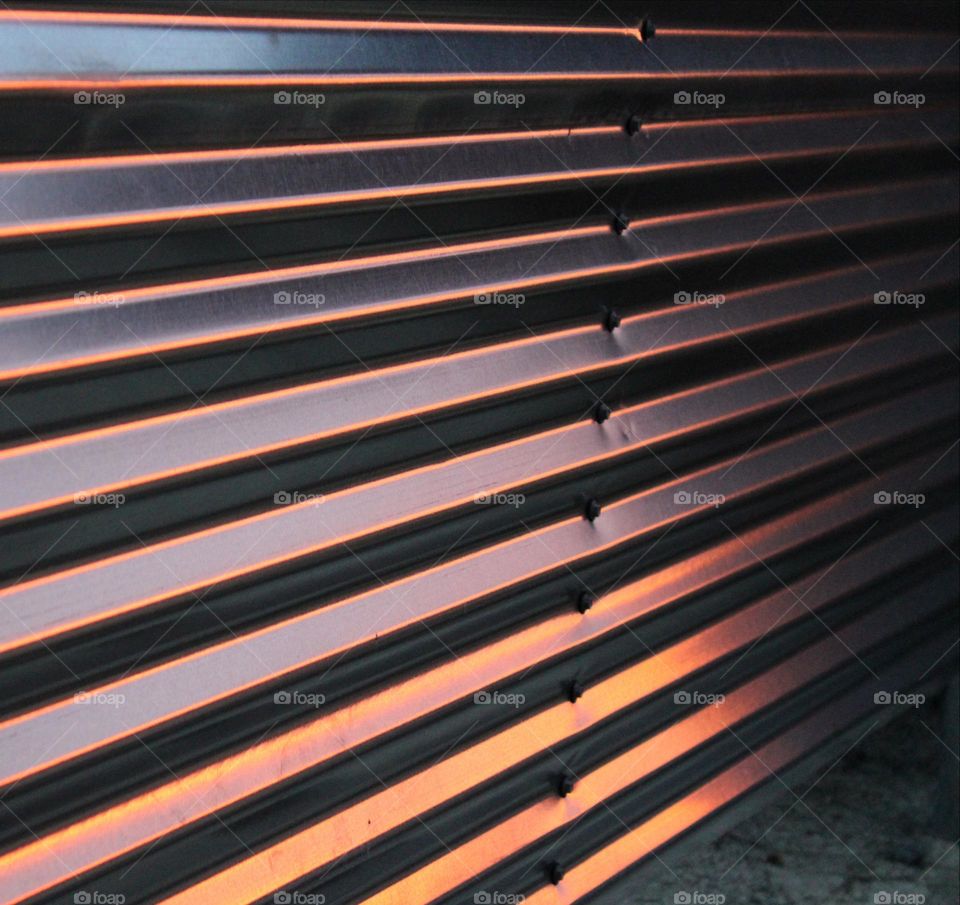 Wood Vs. Metal
corrugated metal fencing with sunrise  reflection.