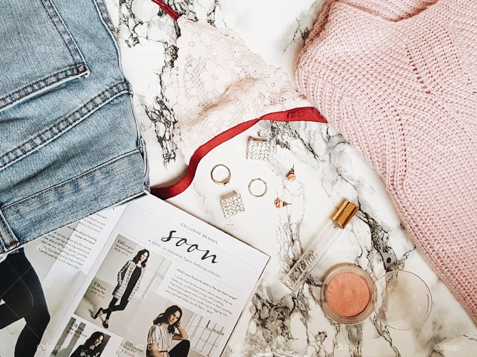 Flatlay showing the process of anyone's routine for looking good and preparing for the day. Look in fashion magazines for inspiration, choose your outfit, add accessories, little bit of makeup, spritz of perfume and you're out the door.