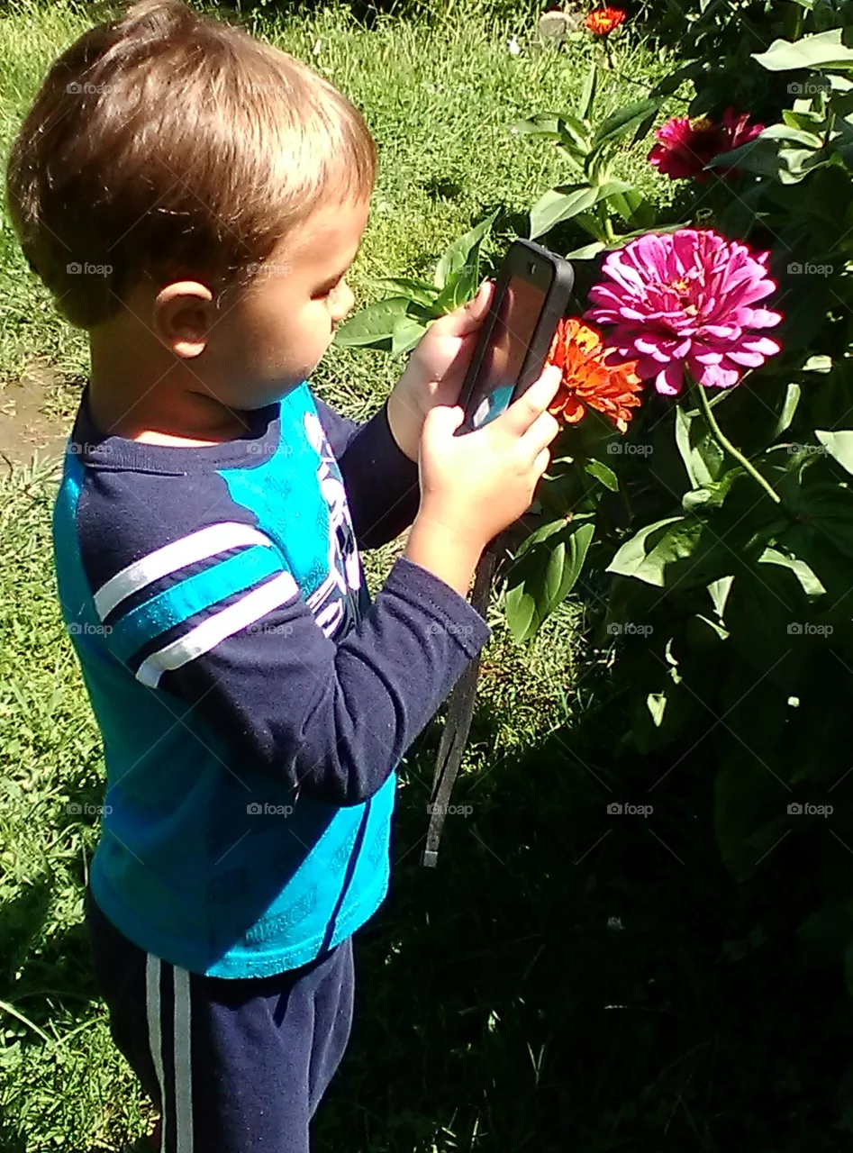 Young Boy Taking Photos of Flowers Like Grandma