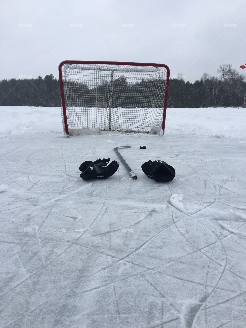 Hockey gloves and stick on a frozen pond