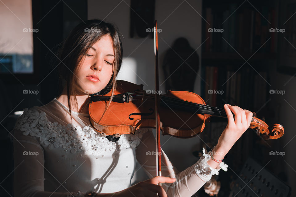 Girl holding a violin in the house