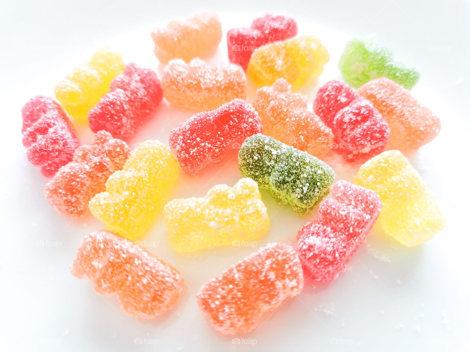 Colourful sour gummy bears on a white plate.