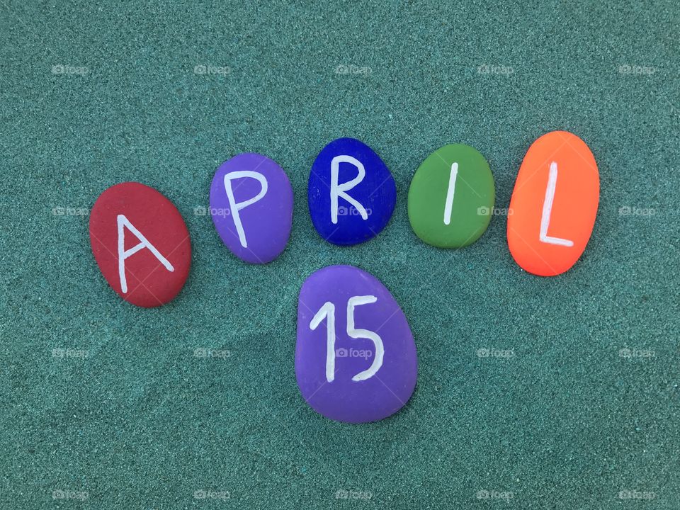 15 April, calendar date on colored stones over green sand 