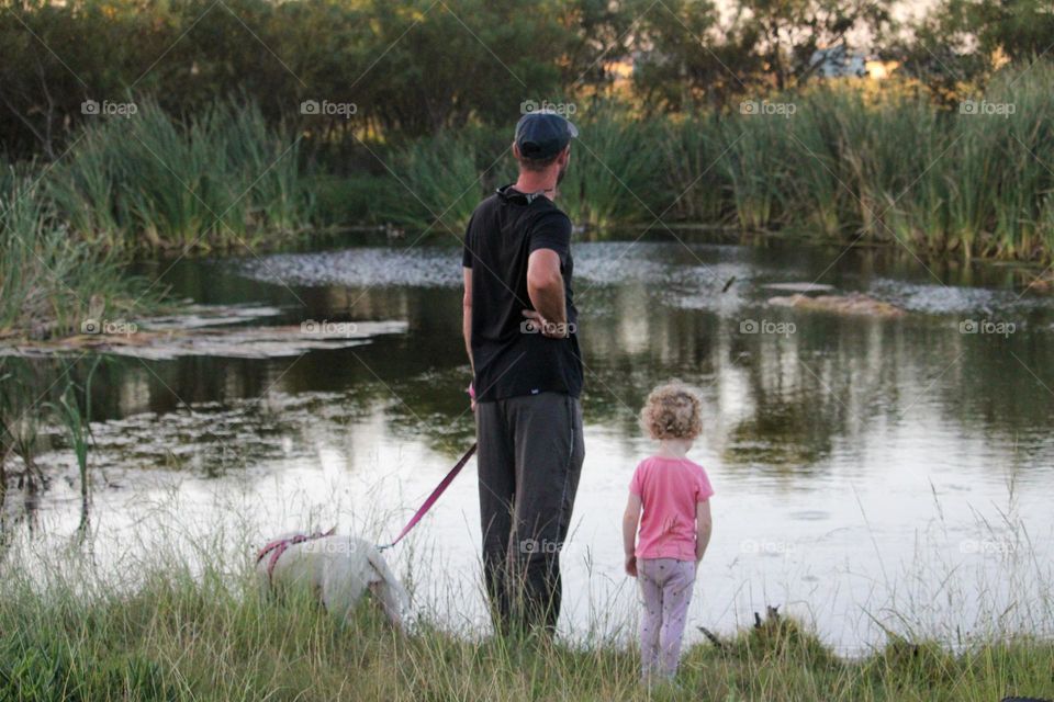 Father and daughter standing at a small pond