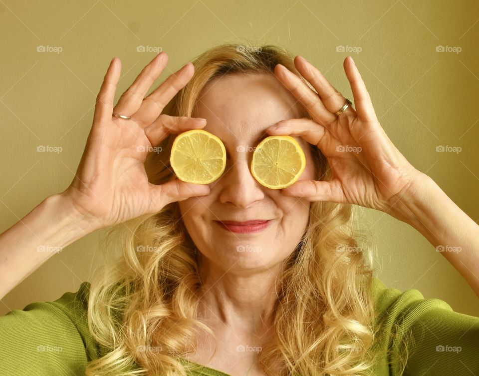 Lemons held in front of the eyes of a blonde woman