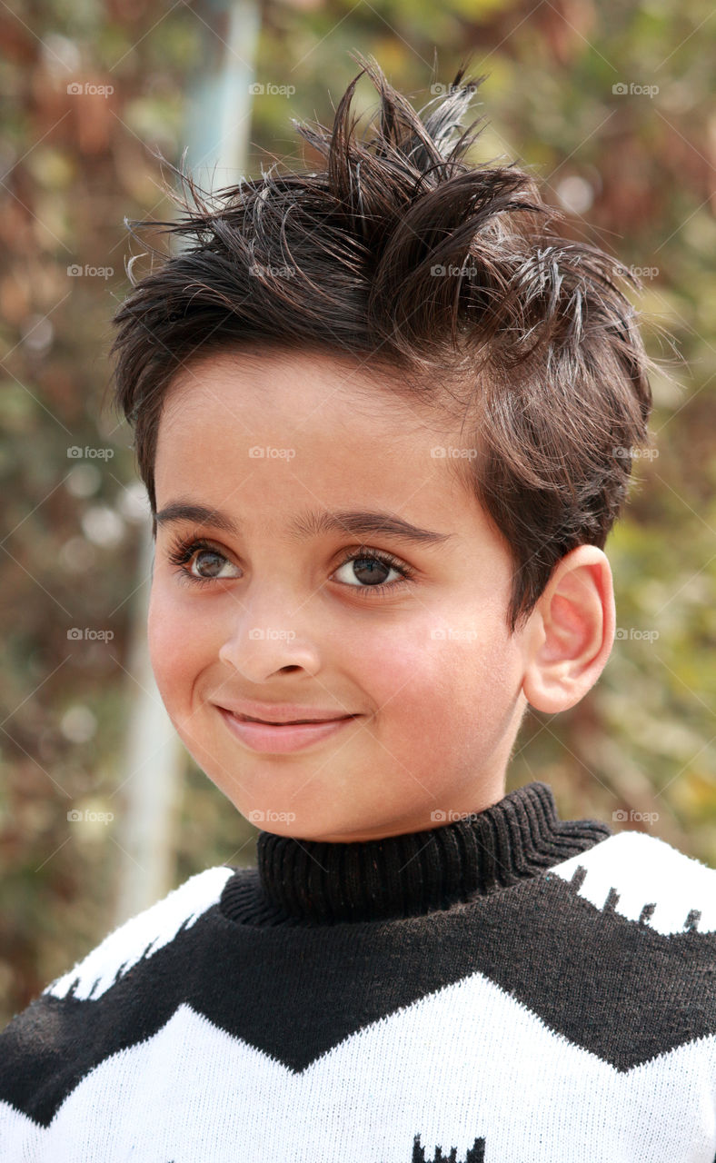 Smiling Indian boy outdoors during winter wearing a warm sweater