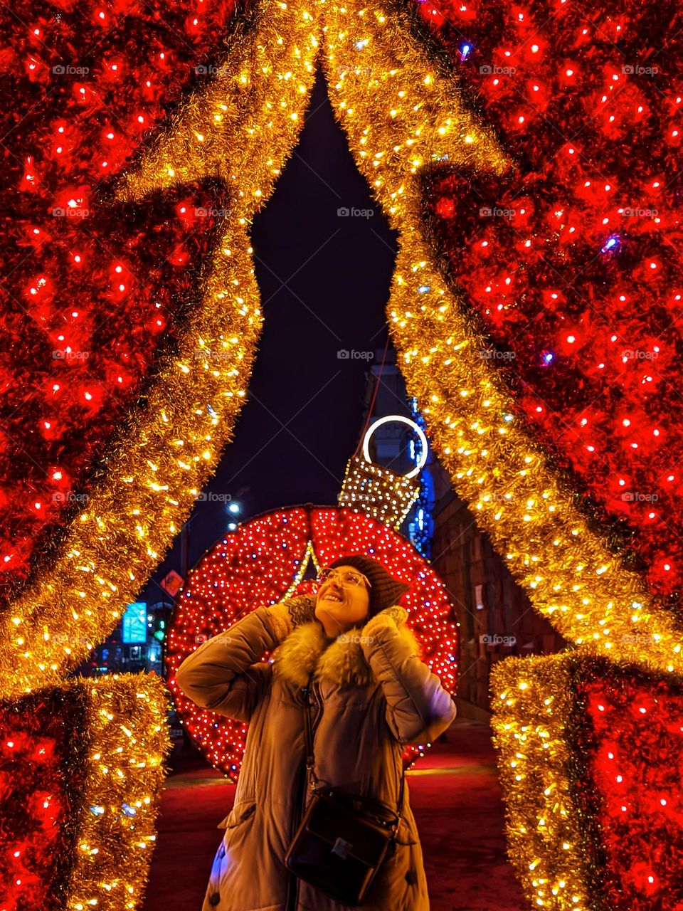 Portrait of young happy, beautiful woman in eye glasses in Christmas,  New Year city with illumination and garlands