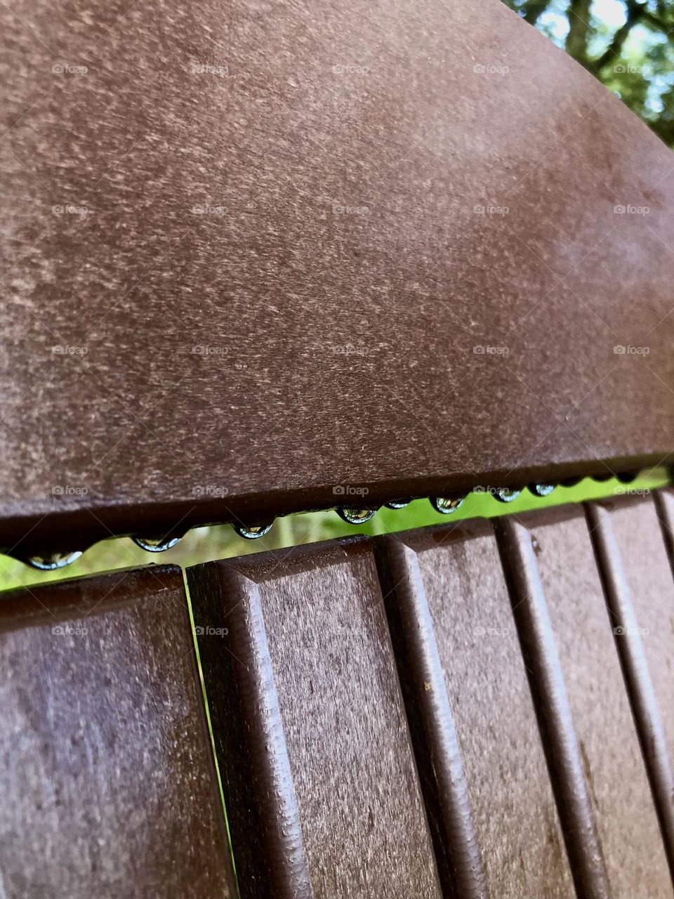 Closeup of the rain left behind on an Adirondack chair, green grass peeking through with a bit of blue sky 💙