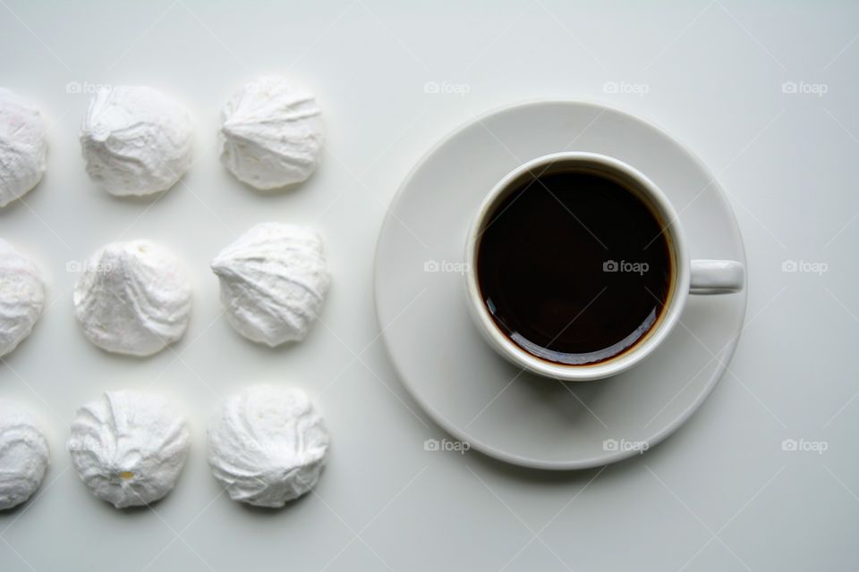 cup of coffee with sweet sugar meringues on a white top view background