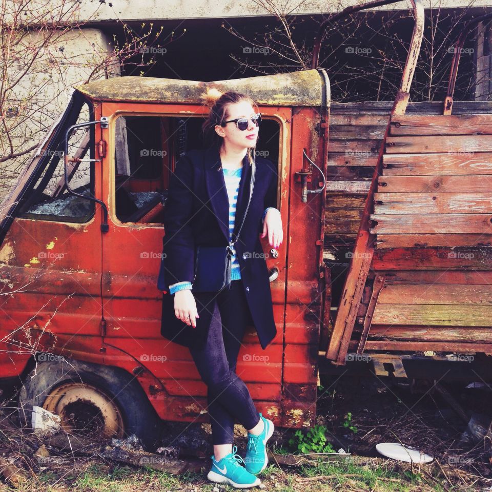 Trendy woman standing in front of vintage vehicle