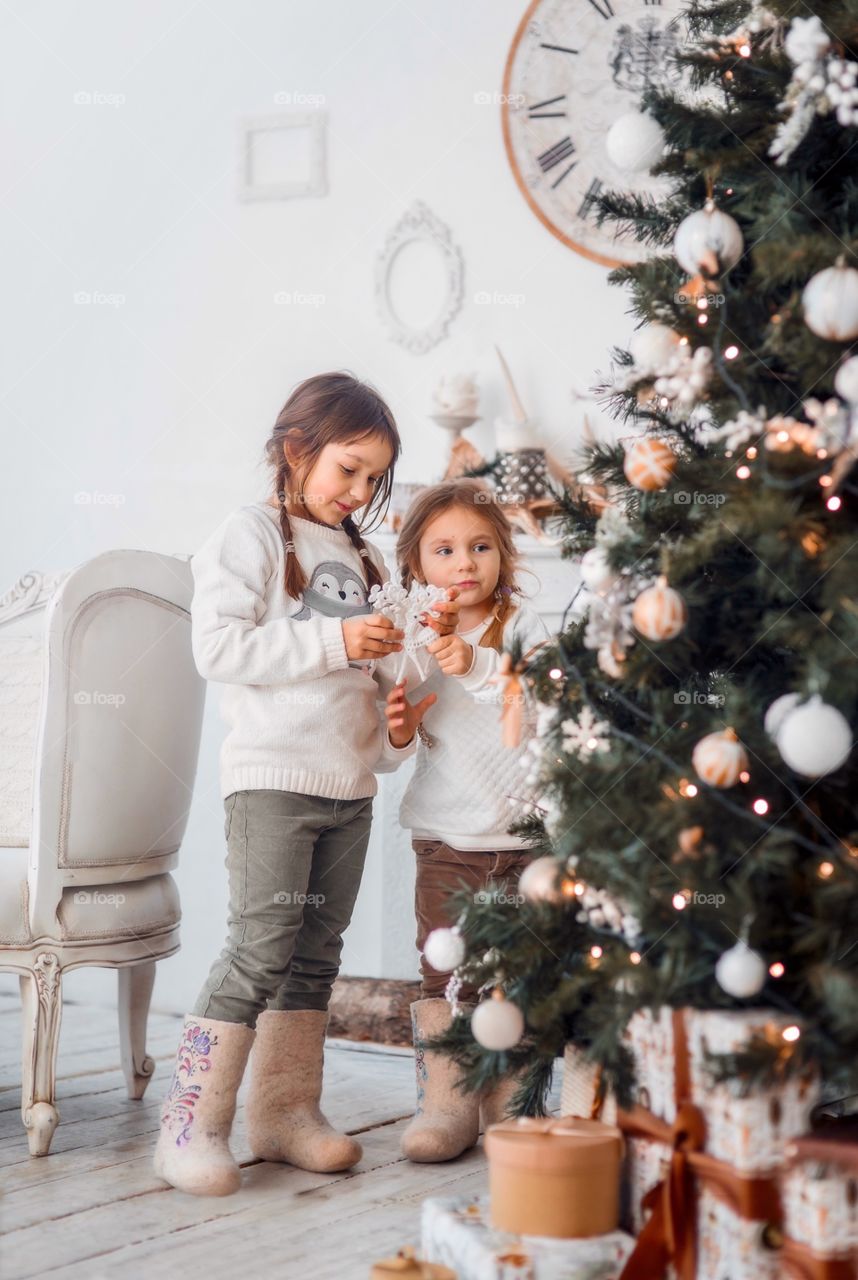 Little girls  in wool boots near Christmas tree 