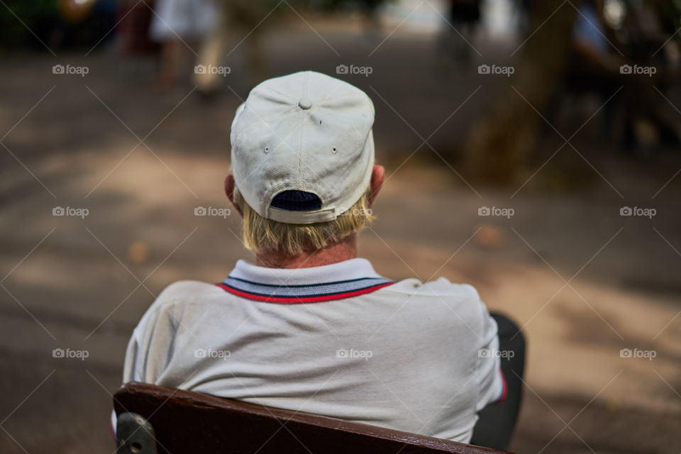 Elderly man with hat sitting in a street bench