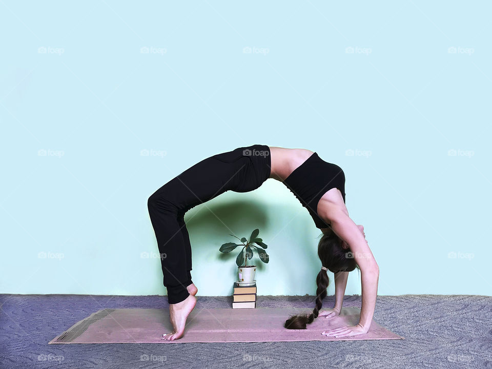 Young woman doing yoga nearby home plant 