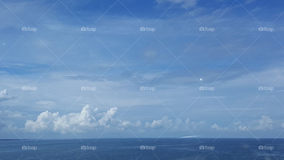 The clouds hang in the sky as the water sways with the breeze.