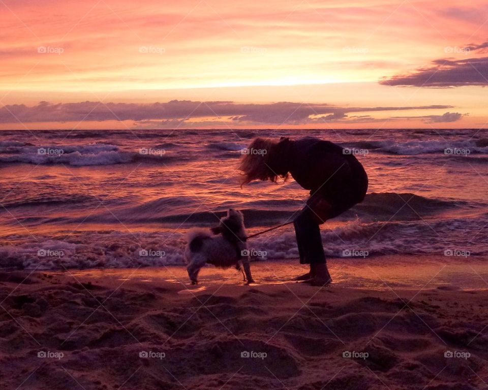 Woman with dog at beautiful sunset over lake michigan