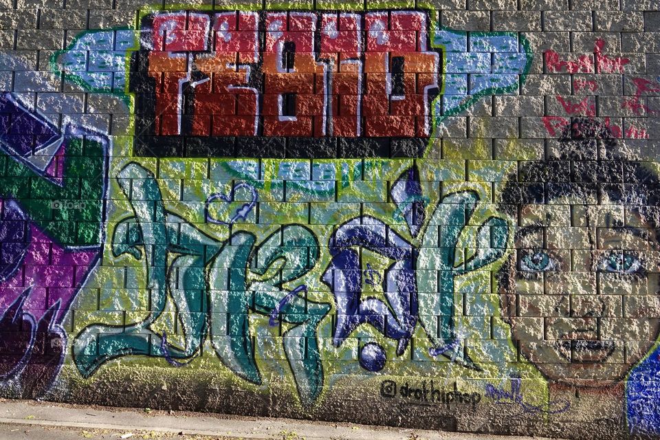 Colorful abstract graffiti and lettering on the brick wall by the path in Krejcarek park in Prague, Zizkov.