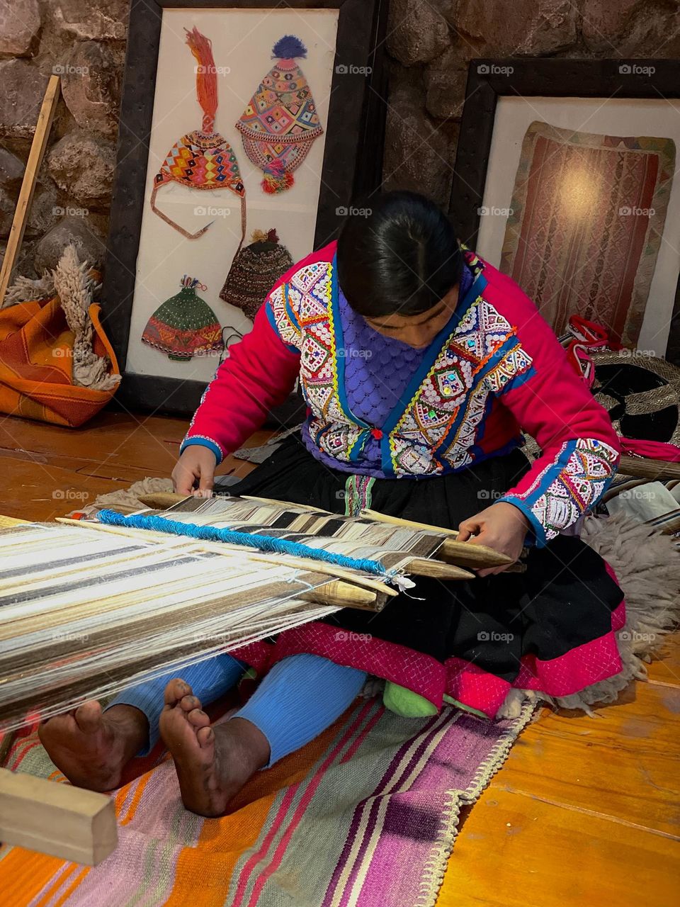 worker from a Peruvian community weaving an alpaca tapestry on a loom